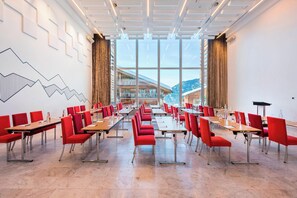 A conference room with red chairs and tables, large windows, and a modern ceiling design.