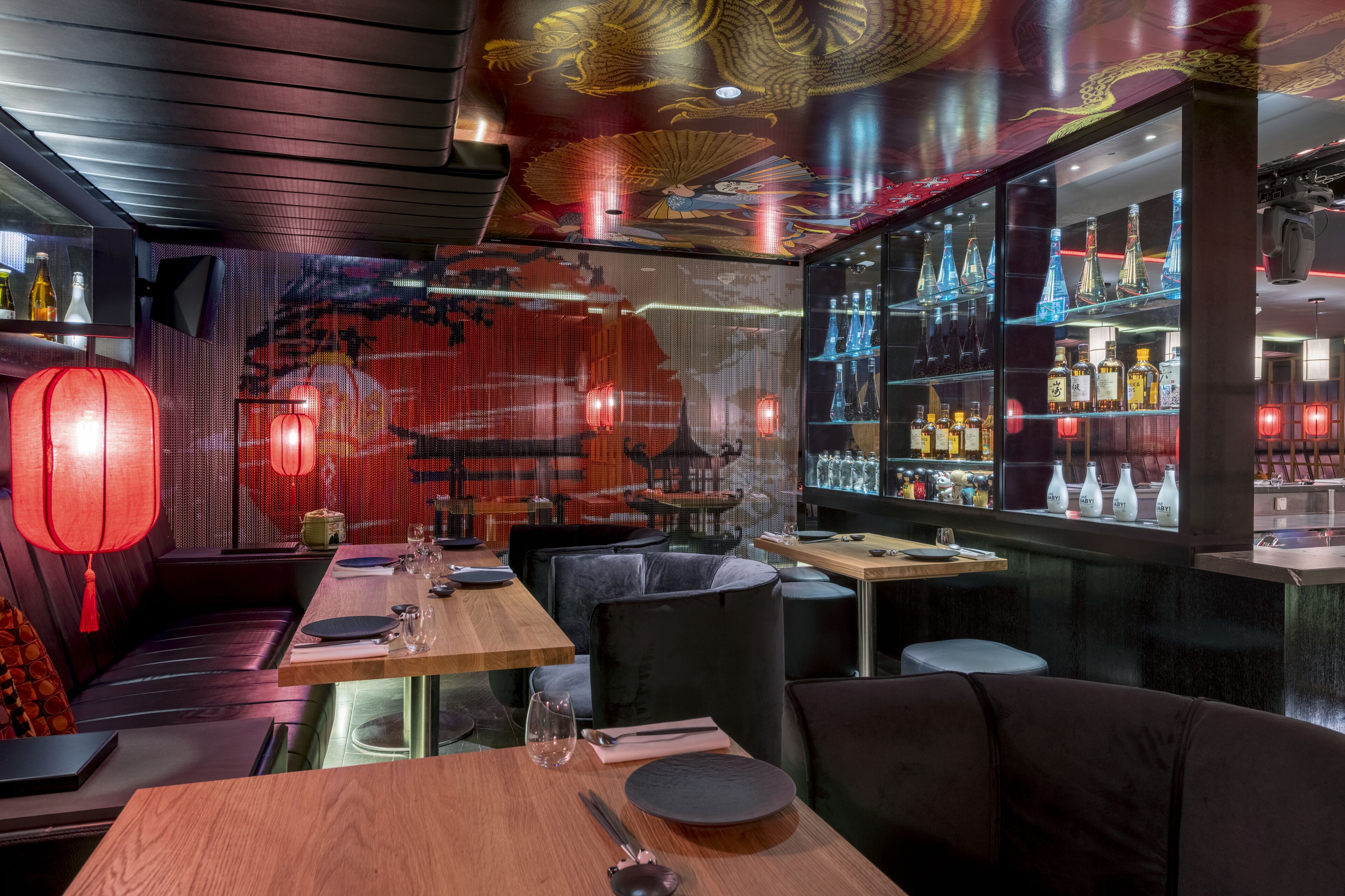A restaurant with a bar area, wooden tables, and red lanterns.