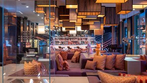 A modern lounge area with a sofa set, patterned cushions, and a glass partition. - W Verbier (Bagnes)