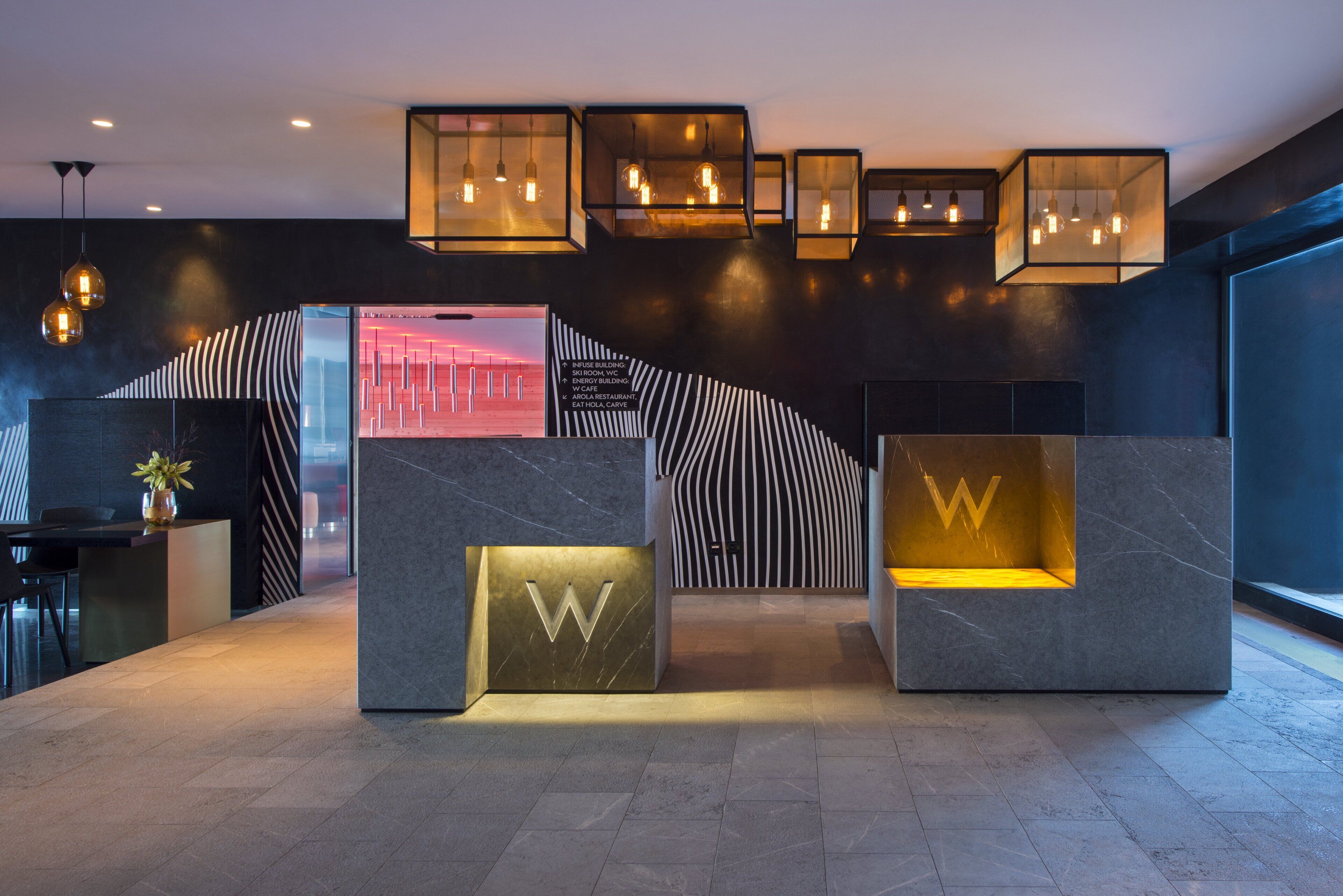 Un espace d’accueil au design moderne, comprenant un comptoir d’accueil, un espace détente agrémenté du logo « W » et une signalétique directionnelle.