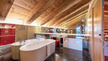 A modern bathroom with a freestanding bathtub, a red shower enclosure, and a large mirror above the sink.
