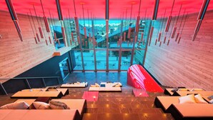 A modern interior with a central glass wall, wooden paneling, and tiered seating areas. - W Verbier (Bagnes)