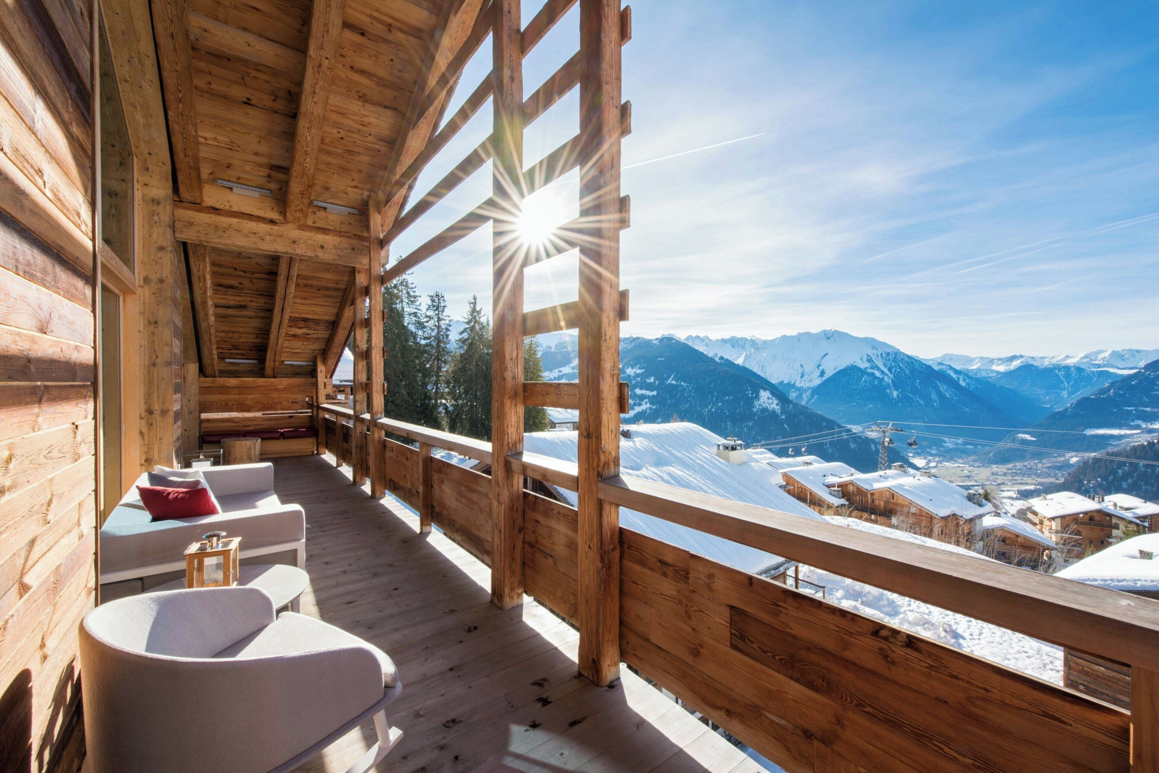 A wooden cabin with a balcony overlooking a snowy mountain landscape.
