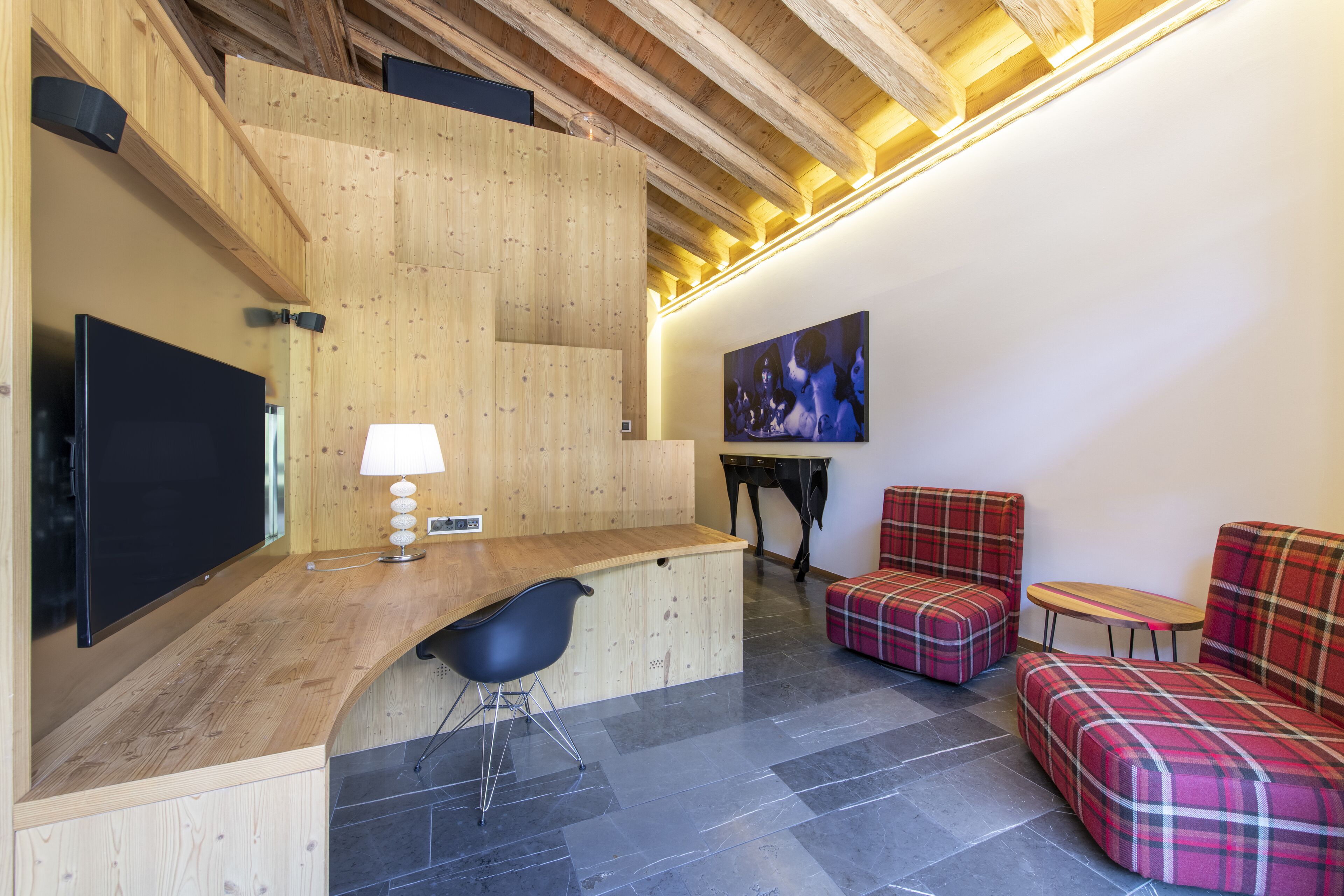 Ein modernes Interieur mit einer Holztresen, schwarzen Stühlen, Karosobas und einem Bild an der Wand.