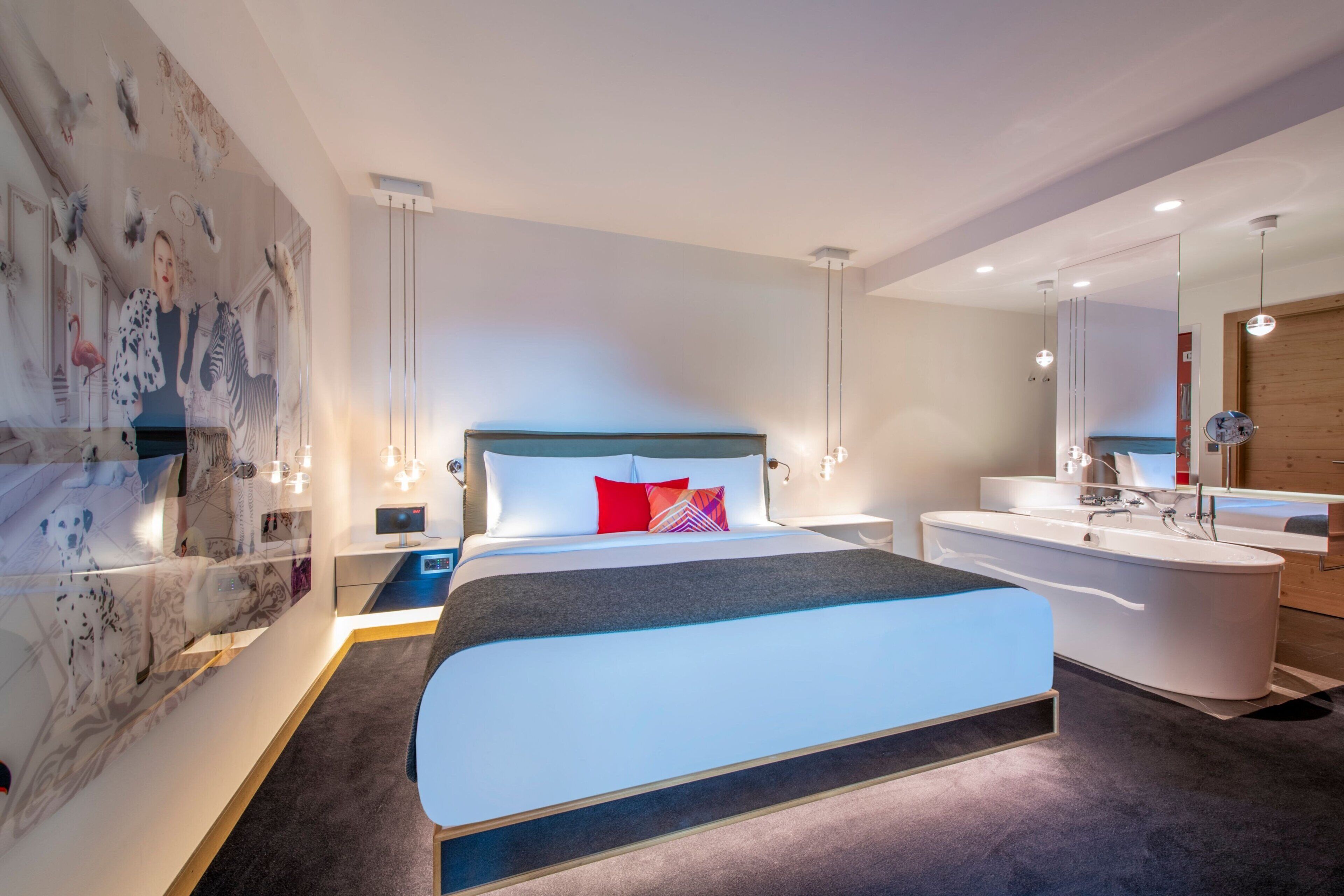 Un dormitorio moderno con una cama grande, una bañera integrada y un tocador empotrado.