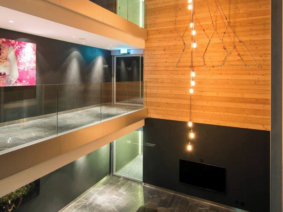 Un interior moderno con pared de madera, lámpara colgante y zona de estar con rocas.