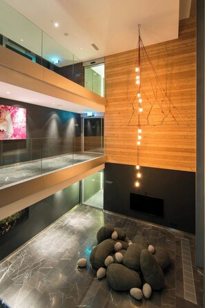 A modern interior with a wooden wall, a hanging light fixture, and a seating area with rocks.