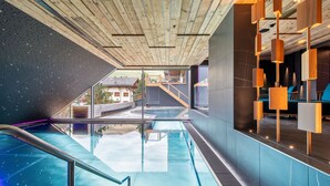 A modern indoor swimming pool with a wooden ceiling and a view of the outside. - W Verbier (Bagnes)