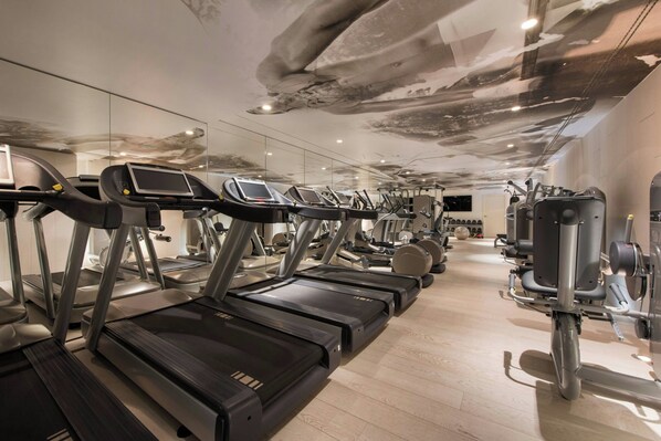 A gym with multiple treadmills, exercise bikes, and weight machines.