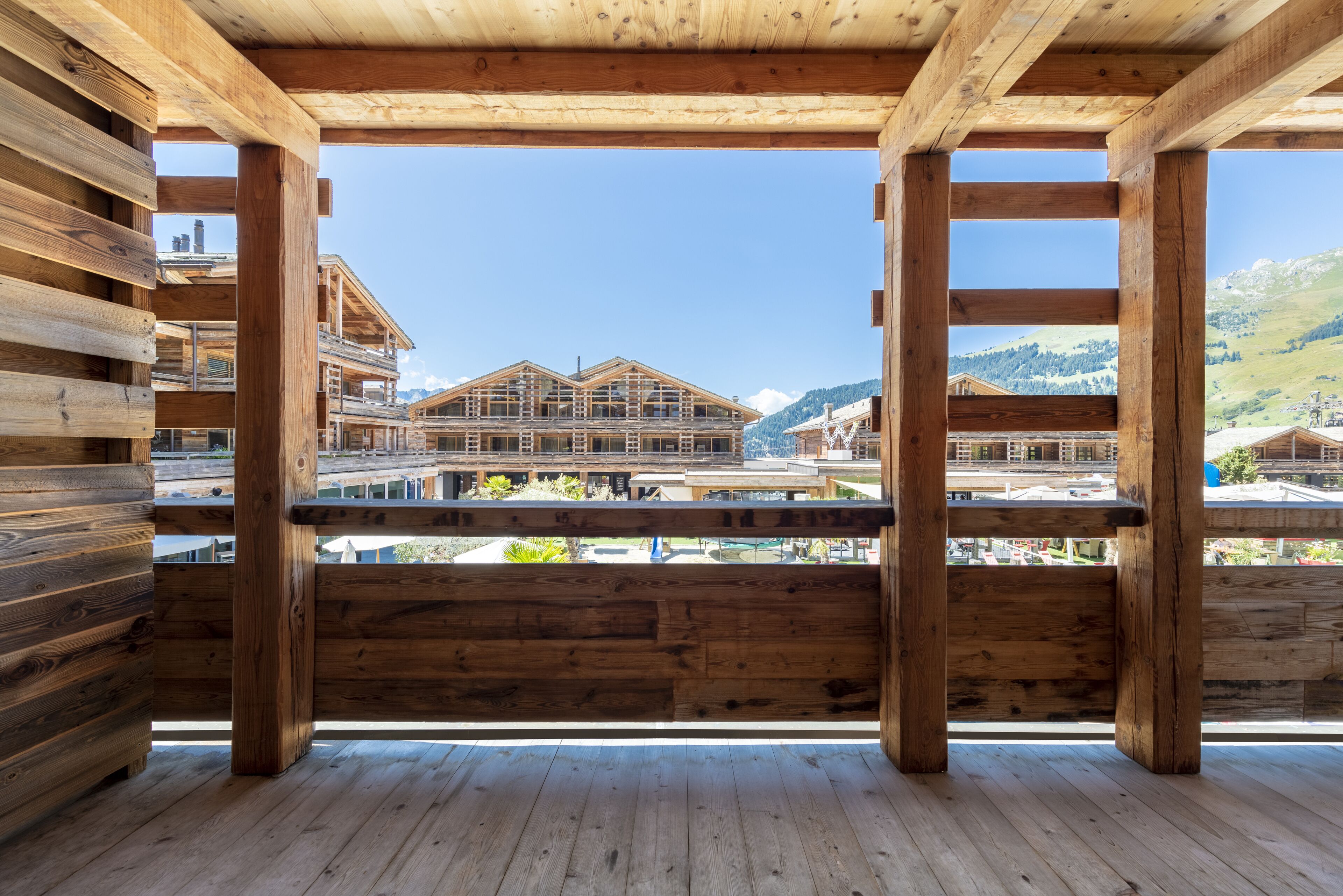 A wooden cabin with a balcony overlooking a mountainous area.