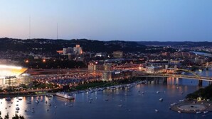 Eine Stadtansicht im Abenddämmerung mit einem Fluss, Booten und einer Brücke.