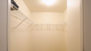 Ein kleiner, leerer begehbarer Kleiderschrank mit einem Wäscheständer aus Metall und einer weißen Tür.