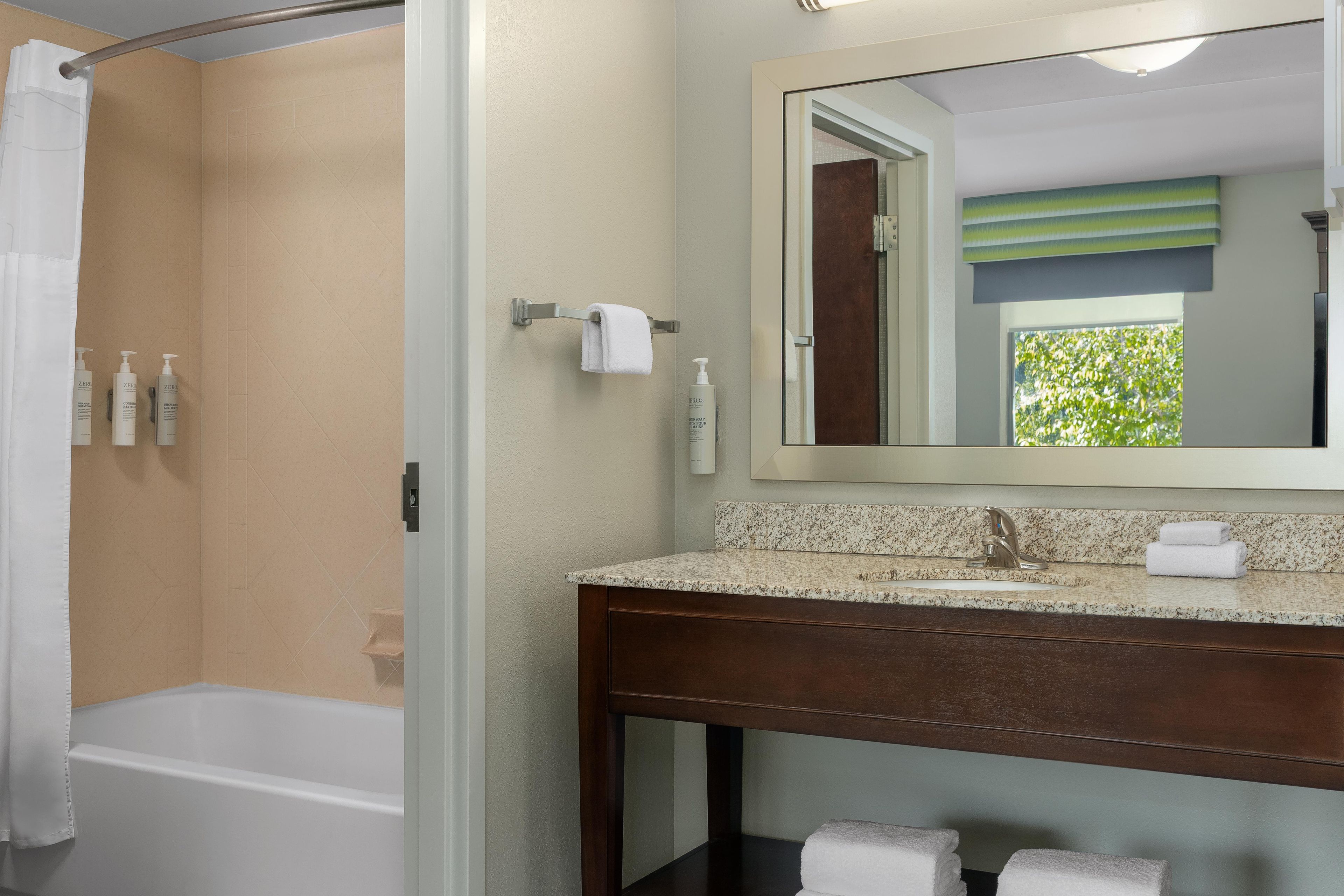 A bathroom with a shower, a sink, and a mirror.