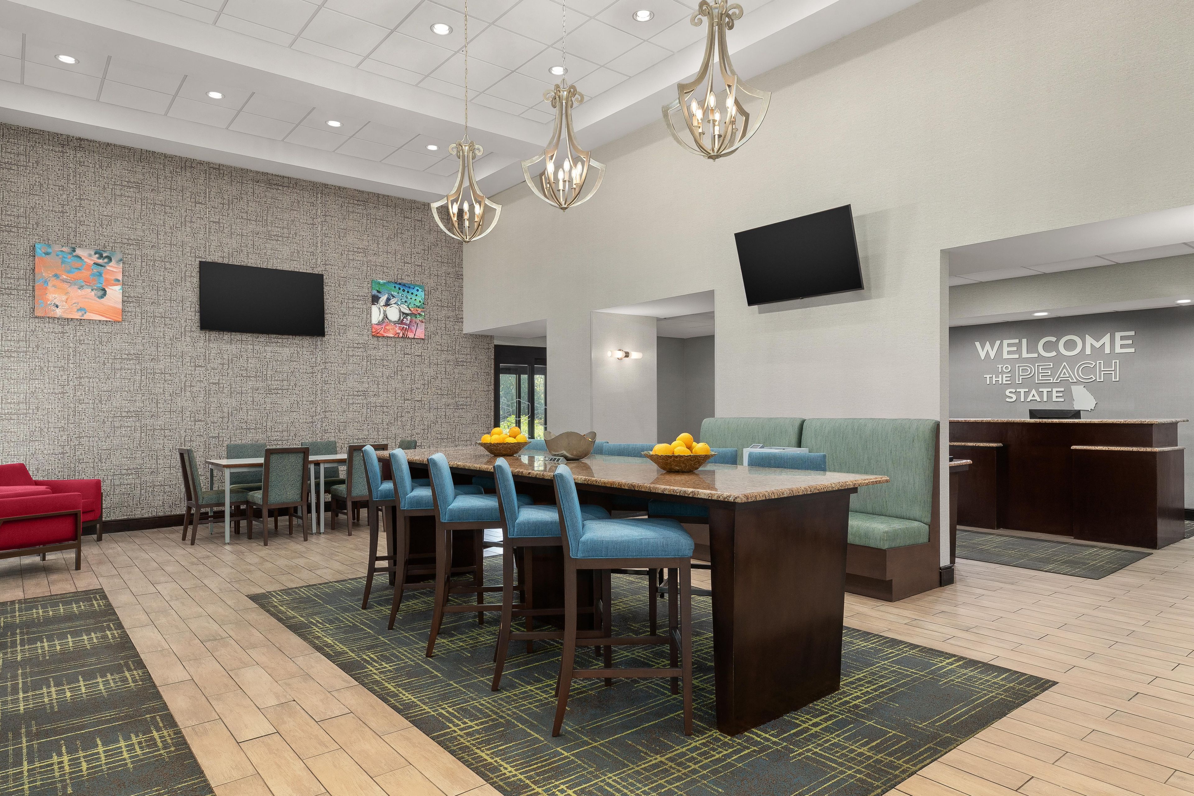 A modern hotel lobby with a dining area, seating, and a reception desk.