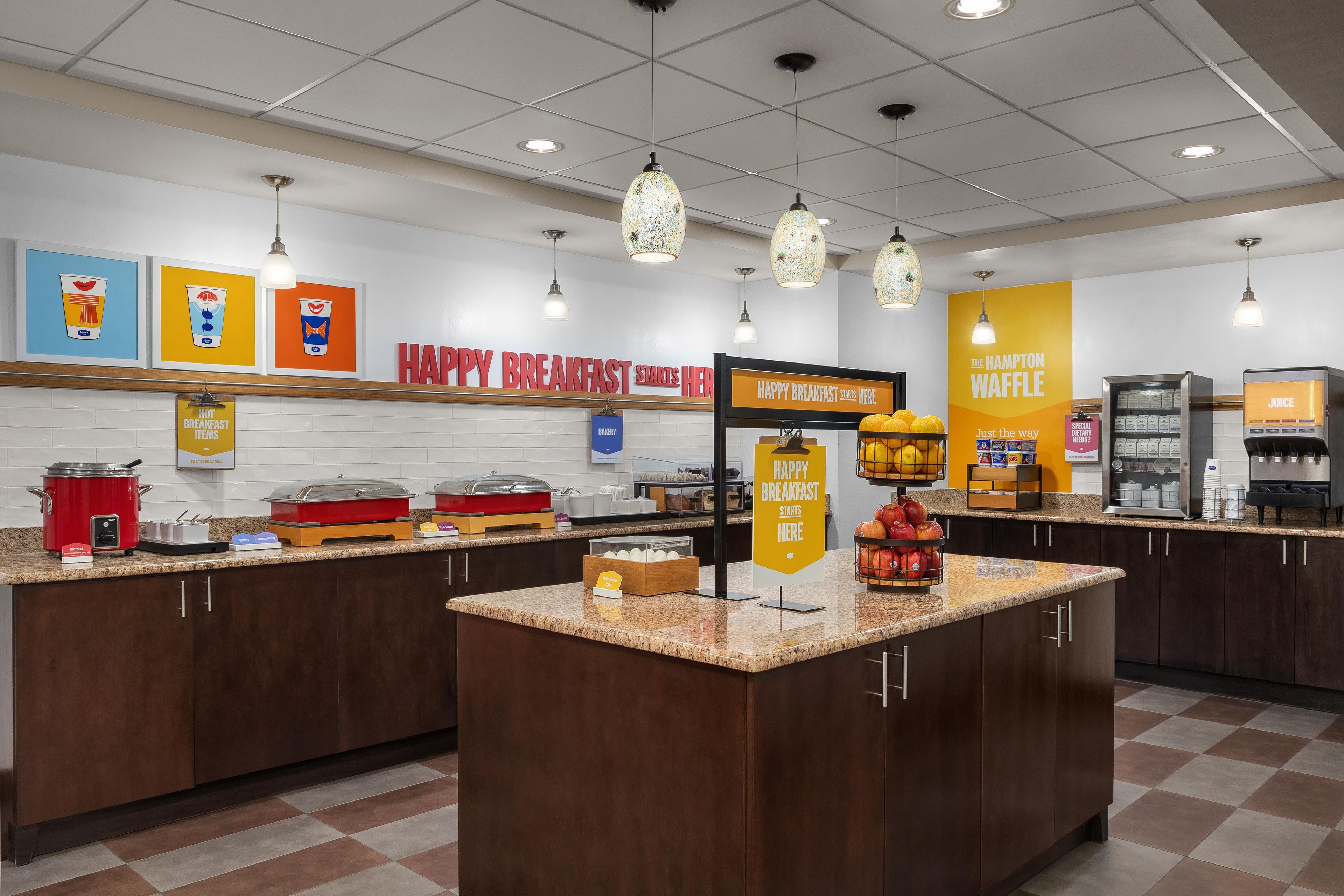 A breakfast buffet area with various food stations, including a bakery and juice bar.