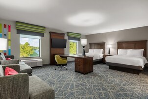 Quarto de hotel com cama, escrivaninha, cadeira e vista para o verde lá fora.