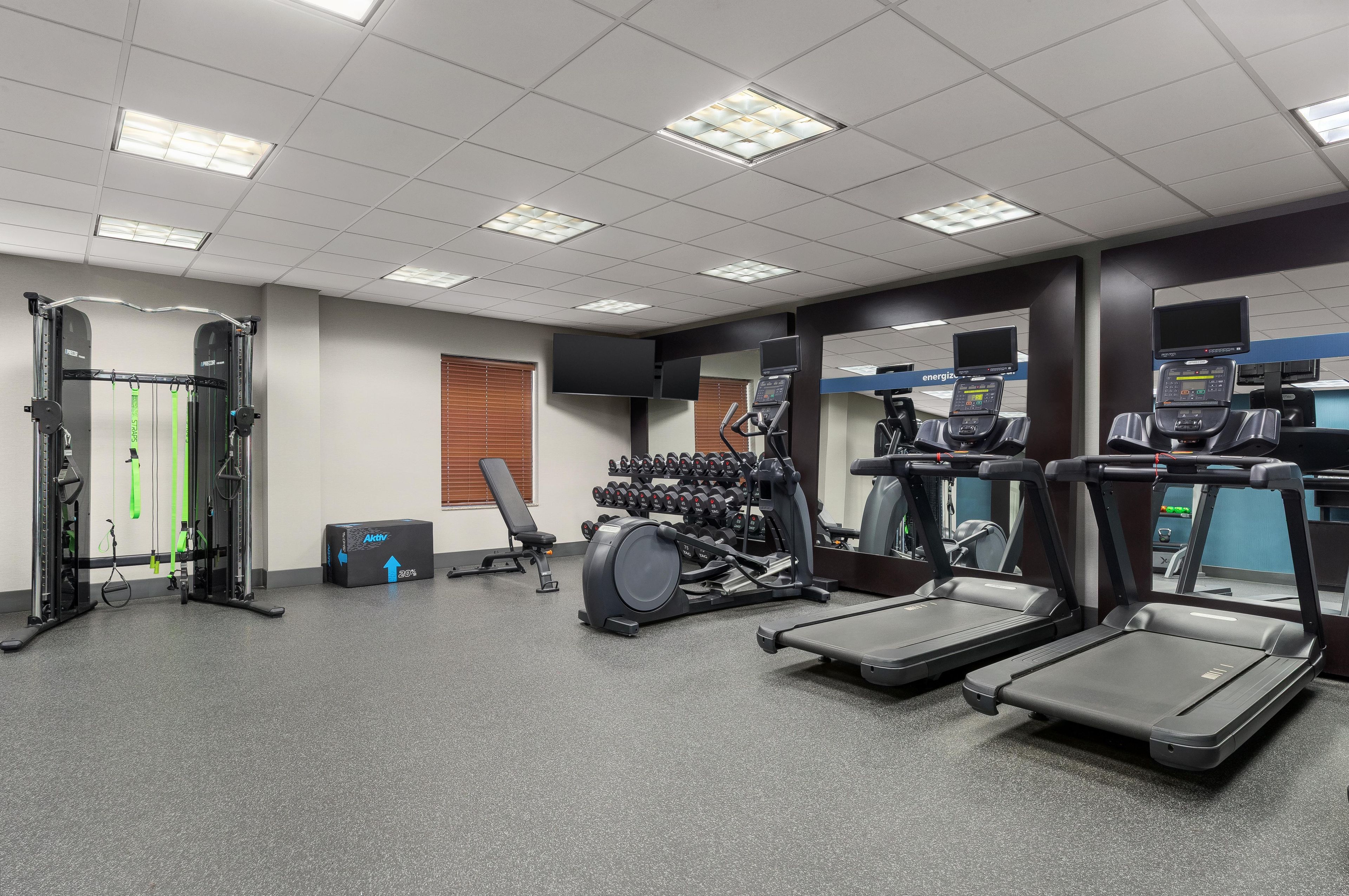 Un gimnasio con cintas de correr, una banca de pesas y diversos equipos de ejercicio.