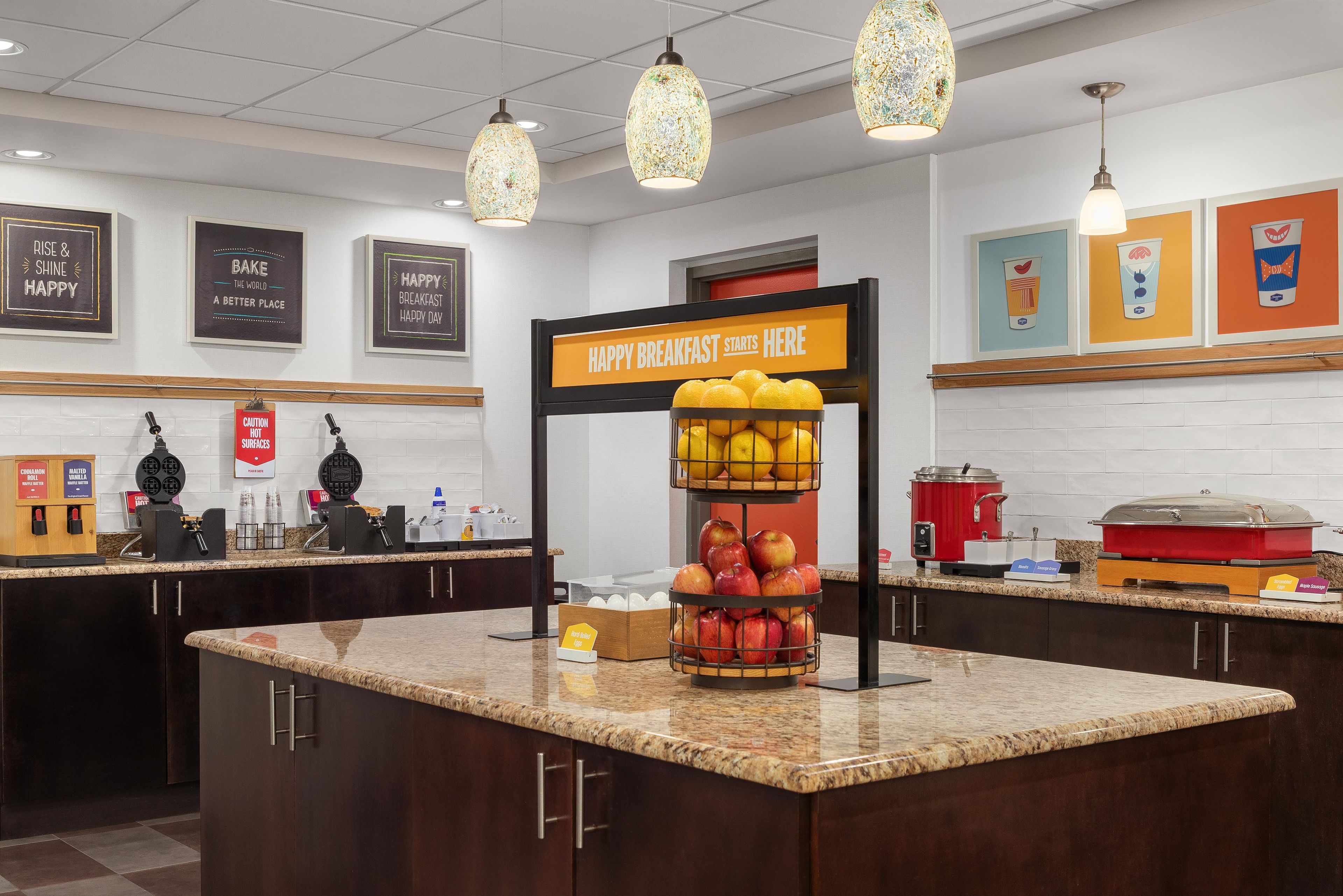 A breakfast station with a sign indicating the start of breakfast, a fruit display, and a coffee machine.