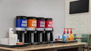 Estación de café con cuatro dispensadores etiquetados como tostado oscuro, tostado claro, descafeinado y agua caliente.