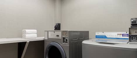 A laundry room with a washing machine, dryer, and a towel rack with folded towels.
