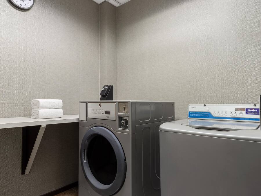 Une buanderie équipée d’un lave-linge, d’un sèche-linge et d’un porte-serviettes où sont pliés les serviettes.