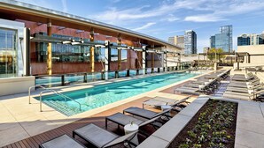 Una piscina en la azotea con sillones de descanso y zona de bar.