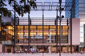 Un hotel modern amb façana de vidre, espais exteriors per seure i una zona d'entrada ben il·luminada.