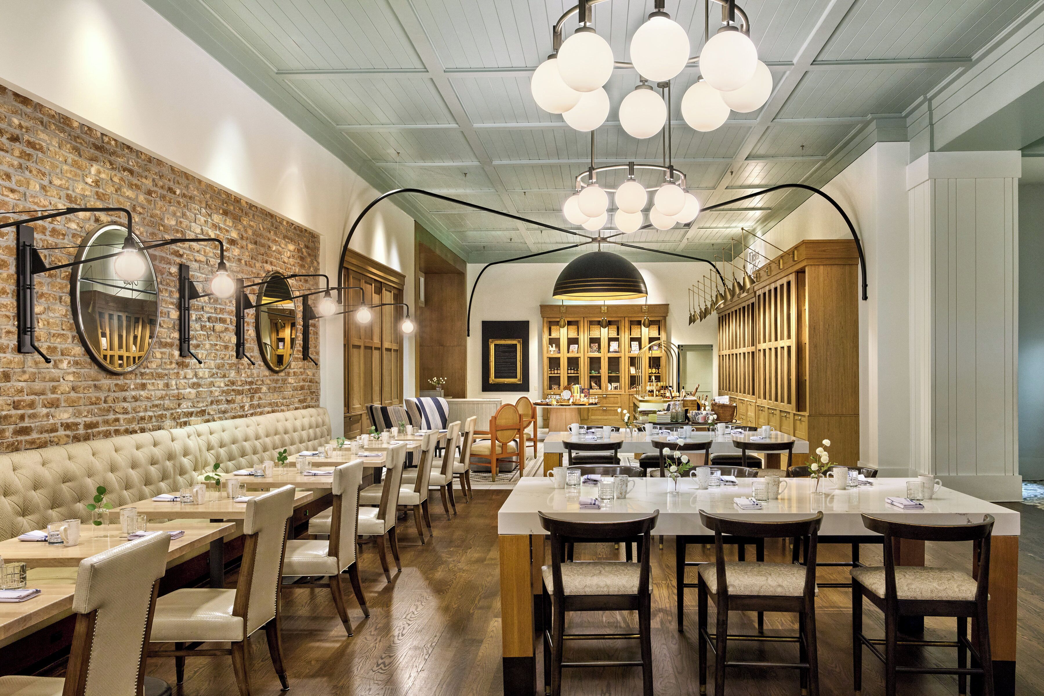 A restaurant with a brick wall, wooden cabinets, and a long bench seating area.