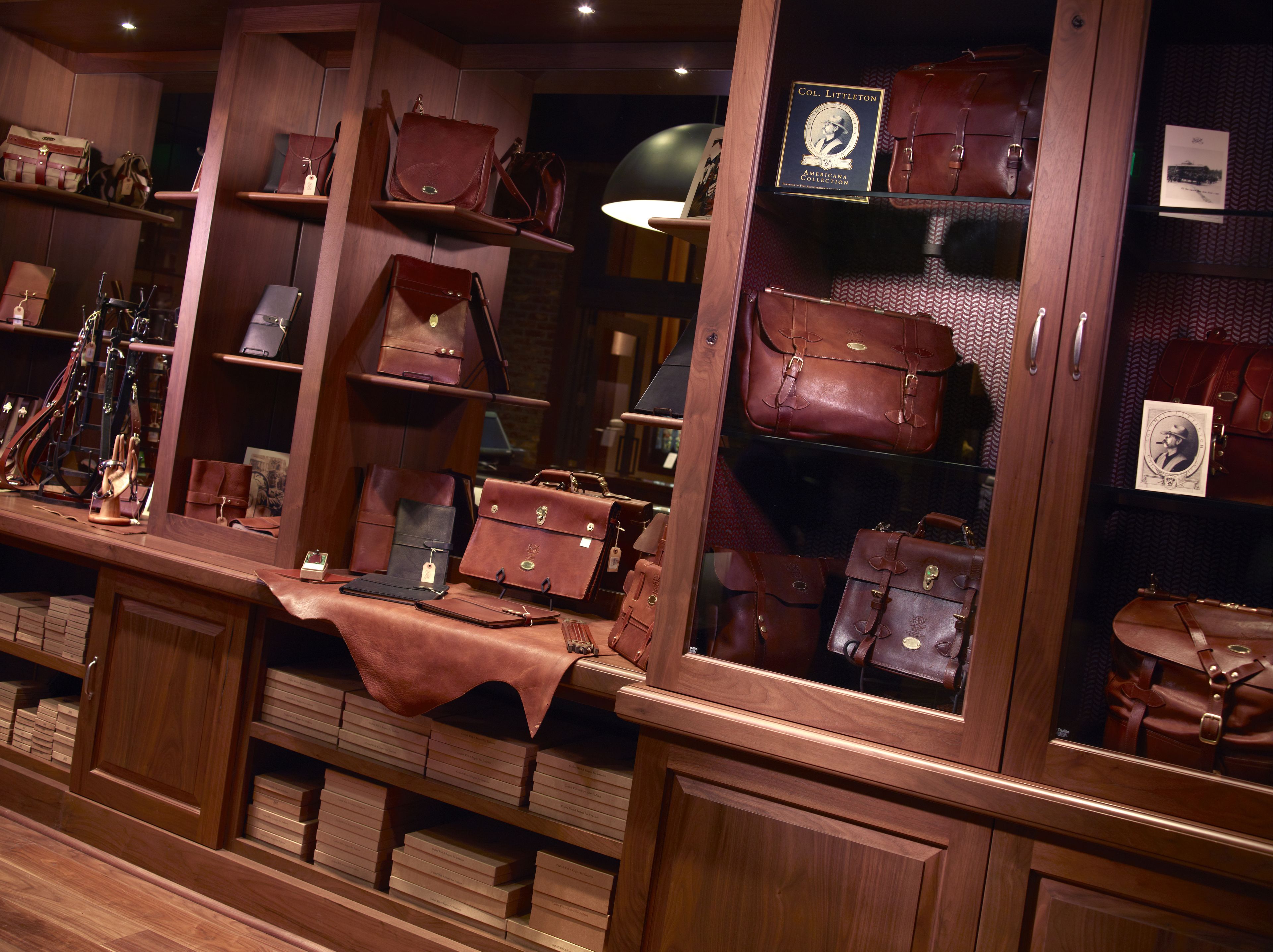 A display of leather goods including bags and boxes, arranged on shelves and counters.