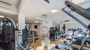 Un gimnasio con varios equipos de ejercicio, una pelota grande y un suelo de madera.