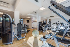 Un gimnasio con varios equipos de ejercicio, una pelota grande y un suelo de madera.