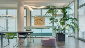 Un interior moderno con una mesa de vidrio, sillas, un pilar de piedra y una planta en maceta.