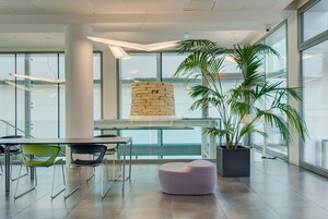 Un interior moderno con una mesa de vidrio, sillas, un pilar de piedra y una planta en maceta.