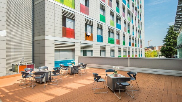 Terraza en la azotea con mobiliario exterior y vista a un edificio moderno con diseños coloridos en las ventanas.
