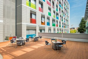 Terraza en la azotea con mobiliario exterior y vista a un edificio moderno con diseños coloridos en las ventanas.
