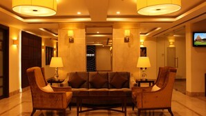 A lobby with a sofa and two armchairs, a television on the wall, and a sign reading "The Black". - Quality Inn Viha (Kumbakonam)