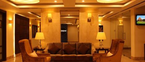 A lobby with a sofa and two armchairs, a television on the wall, and a sign reading "The Black".