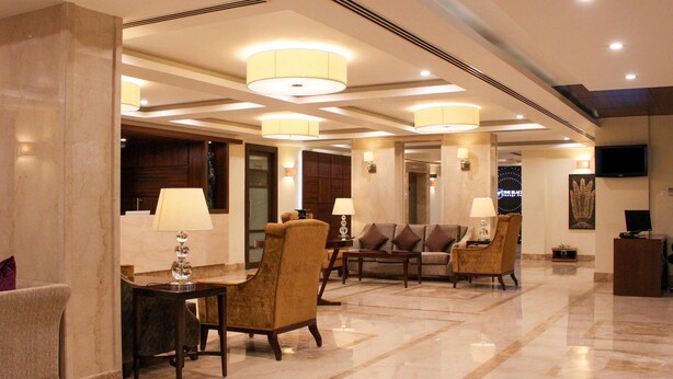 A spacious lobby with a high ceiling, multiple seating areas, and a television mounted on the wall. - Quality Inn Viha (Kumbakonam)