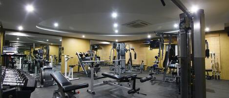 A gym with various exercise equipment, including dumbbells, benches, and weight machines.