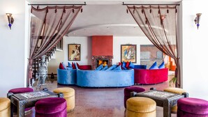 A modern living room with a fireplace, blue and red sofas, and a staircase.