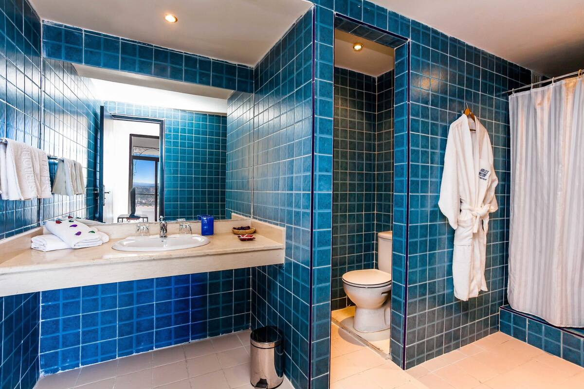 Un baño con azulejos azules, un lavabo, un inodoro y una cortina de ducha.