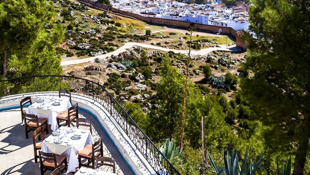 A restaurant with outdoor seating overlooking a mountainous landscape.
