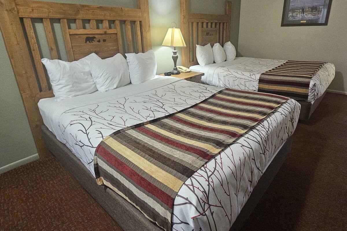 A double bed with a striped blanket and a headboard with a wooden design.