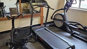 Un gimnasio con cintas de correr, una elíptica y una bicicleta estática.