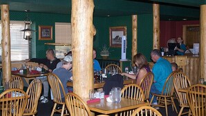 Un restaurante con pilares, sillas y mesas de madera.