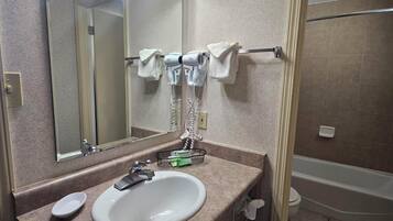 Un baño con lavamanos, espejo, toallero y zona de ducha.