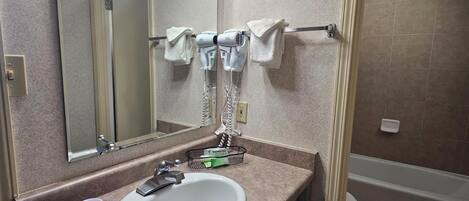 Un baño con lavamanos, espejo, toallero y zona de ducha.