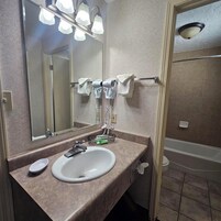 Un baño con lavamanos, espejo, toallero y zona de ducha.