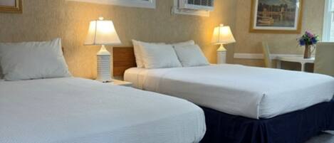A hotel room with two beds, a desk, and a chair.