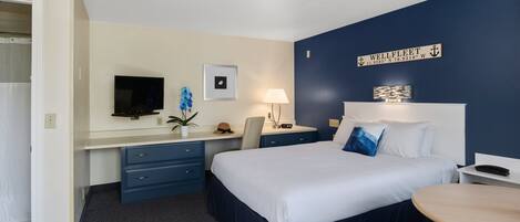 A hotel room with a bed, desk, chair, and a small table.